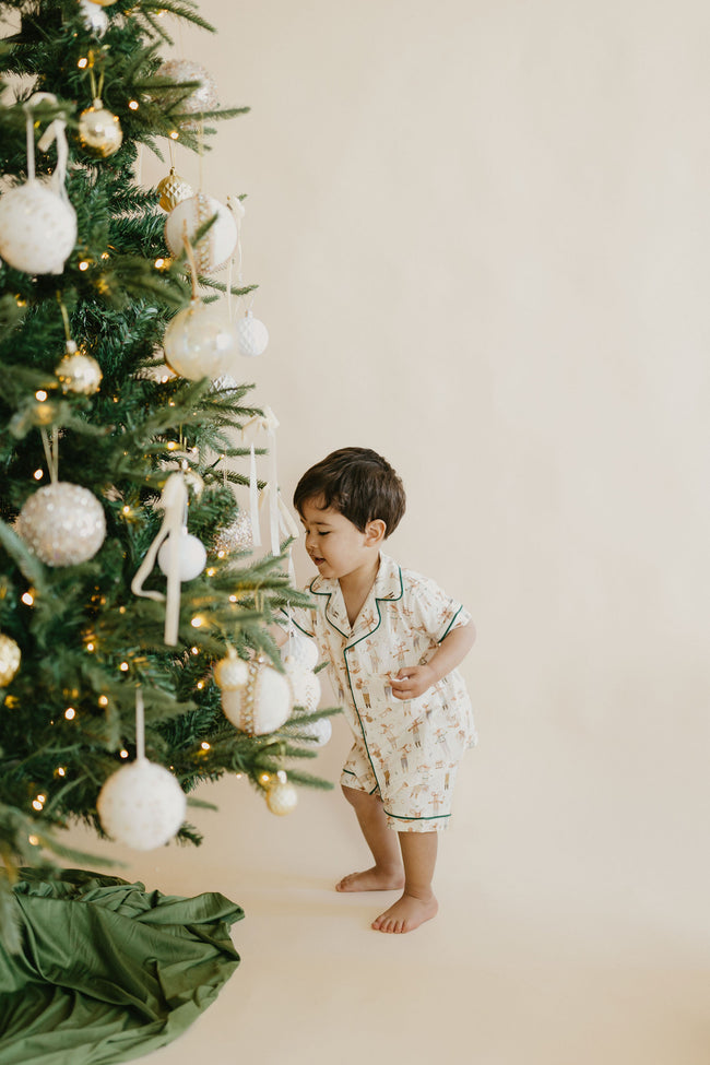 Little boy in Christmas pyjamas beside a decorated Christmas tree